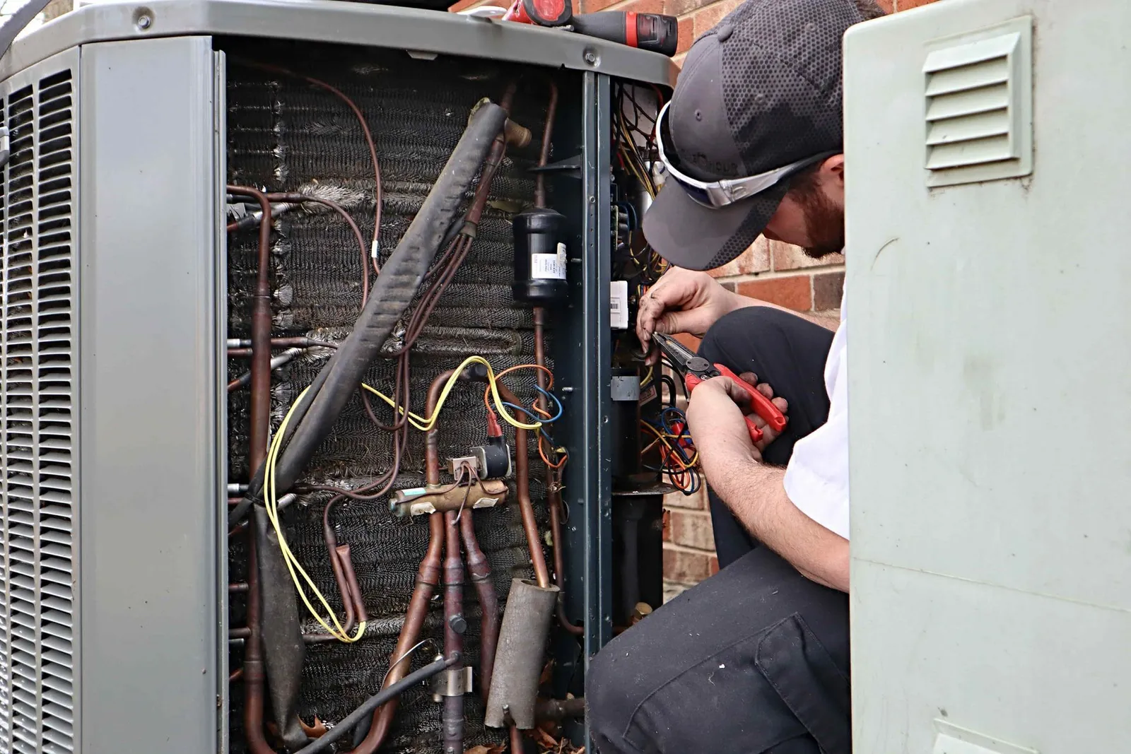 A man is working on an air conditioner outside of a building.