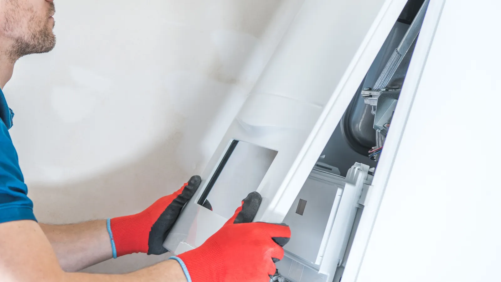 A man wearing red gloves is working on a heating system.
